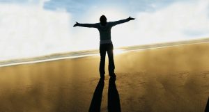 An image of a person in a field with their arms up in the air in worship.